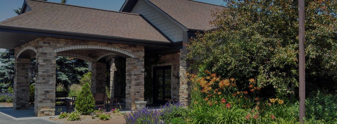 Stone-and-stucco house with a brown tiled roof and landscaped garden.