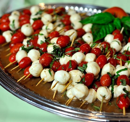 Caprese skewers with cherry tomatoes, mozzarella, and basil arranged on a silver tray