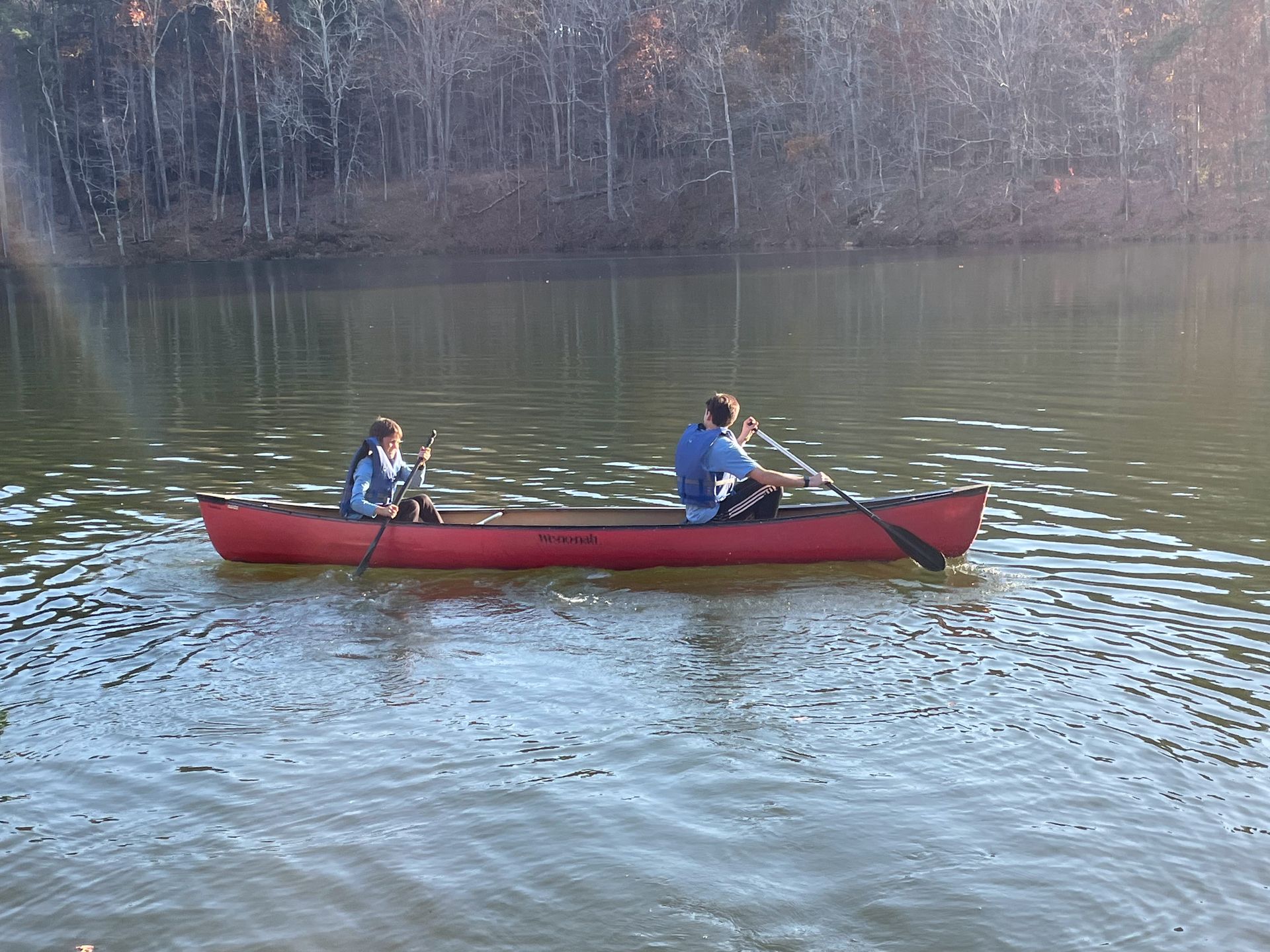 Two people are in a red canoe on a lake.