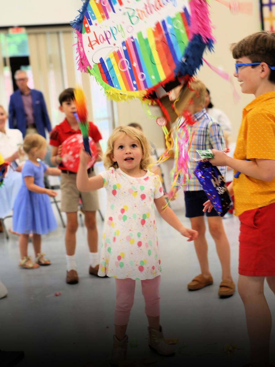 A little girl is holding a pinata that says happy birthday