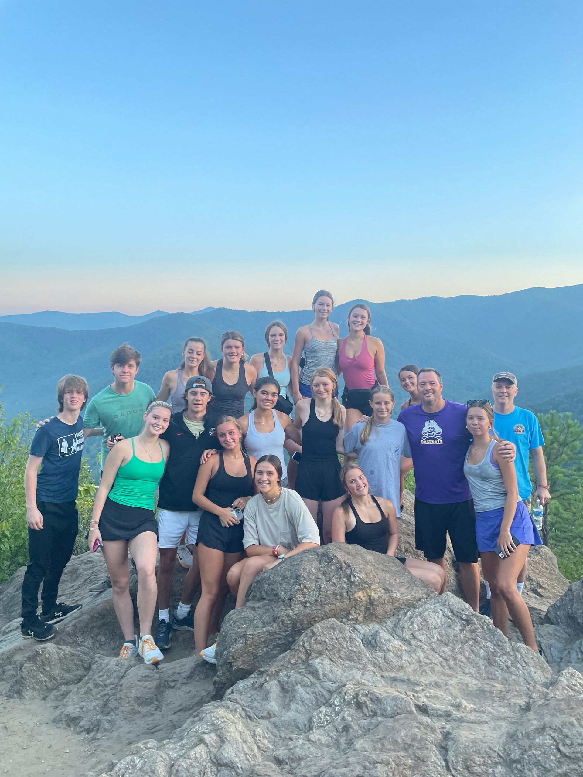A group of people are posing for a picture on top of a mountain.