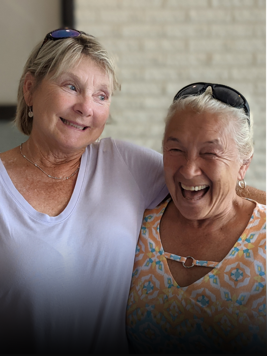 Two older women are hugging each other and smiling.