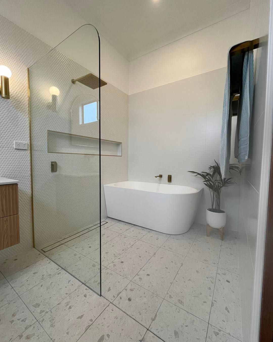 Modern White Bathroom With Freestanding Tub, Glass Shower Screen, and Textured Tile Flooring — Cobra Plumbing & Bathrooms in Kiama, NSW