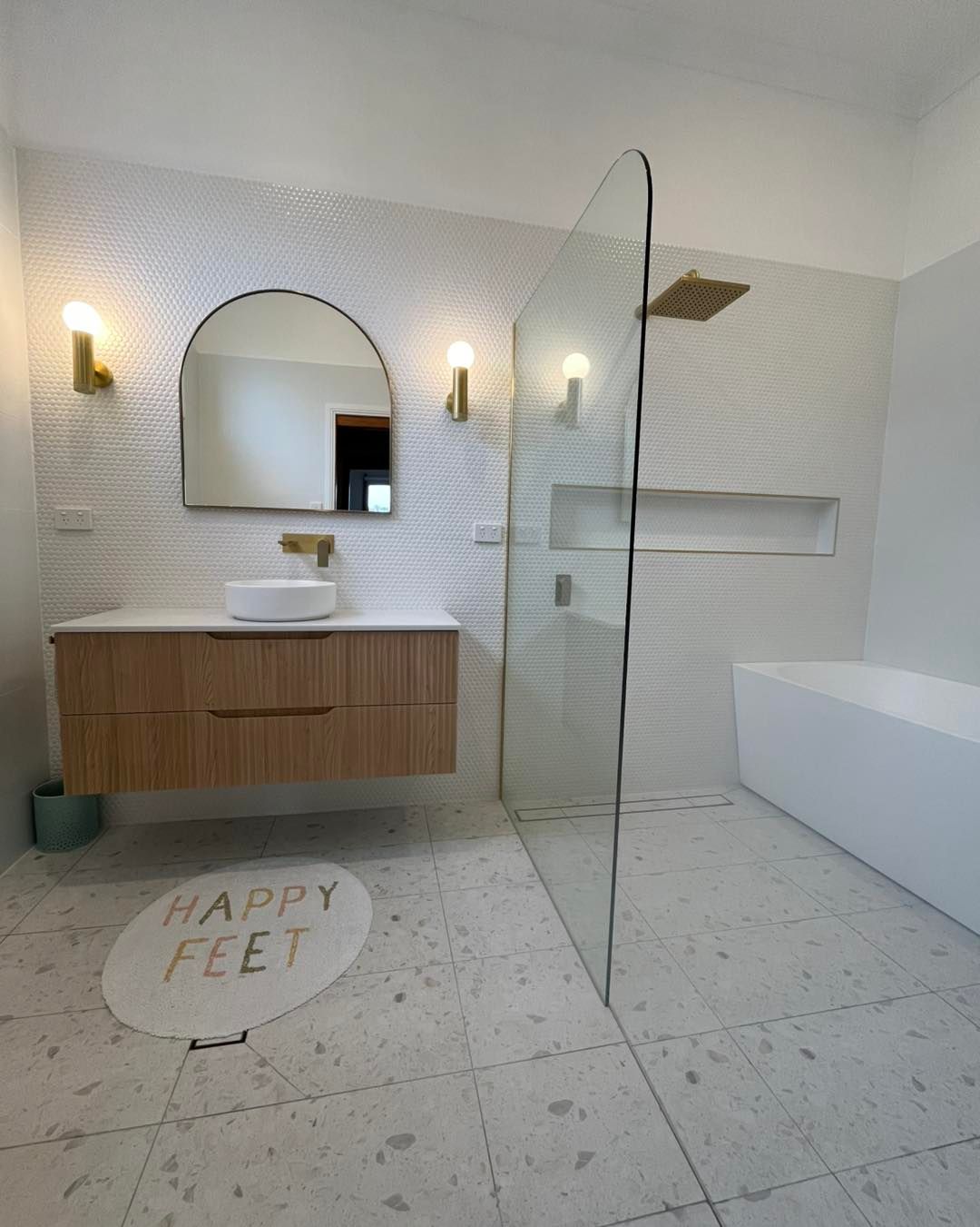 Modern Bathroom With Wooden Vanity, Arched Mirror, Glass Shower, and White Tile — Cobra Plumbing & Bathrooms in Kiama, NSW