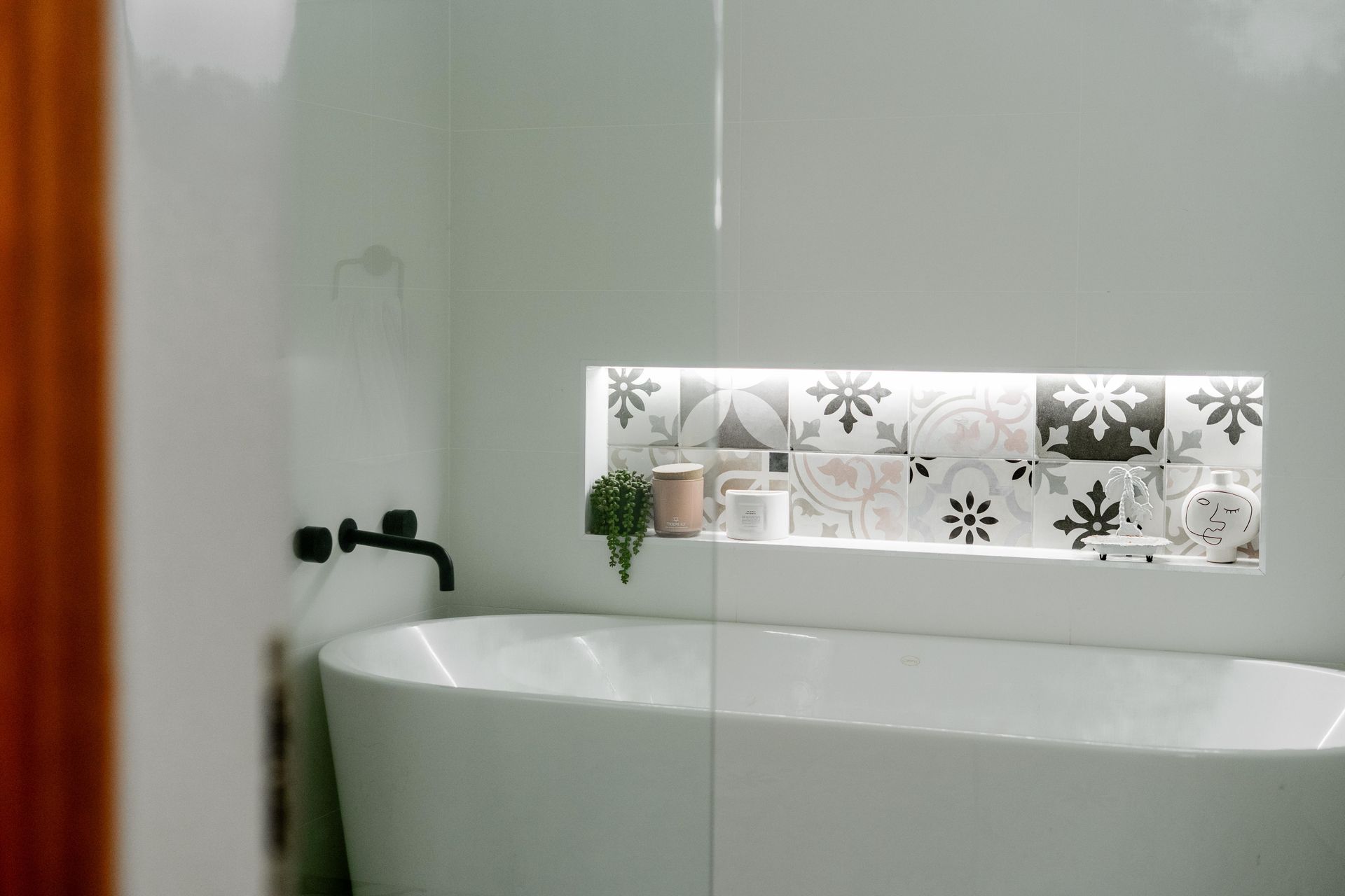 White bathroom with a freestanding tub and a patterned frosted window above it — Cobra Plumbing & Bathrooms in Heathcote, NSW