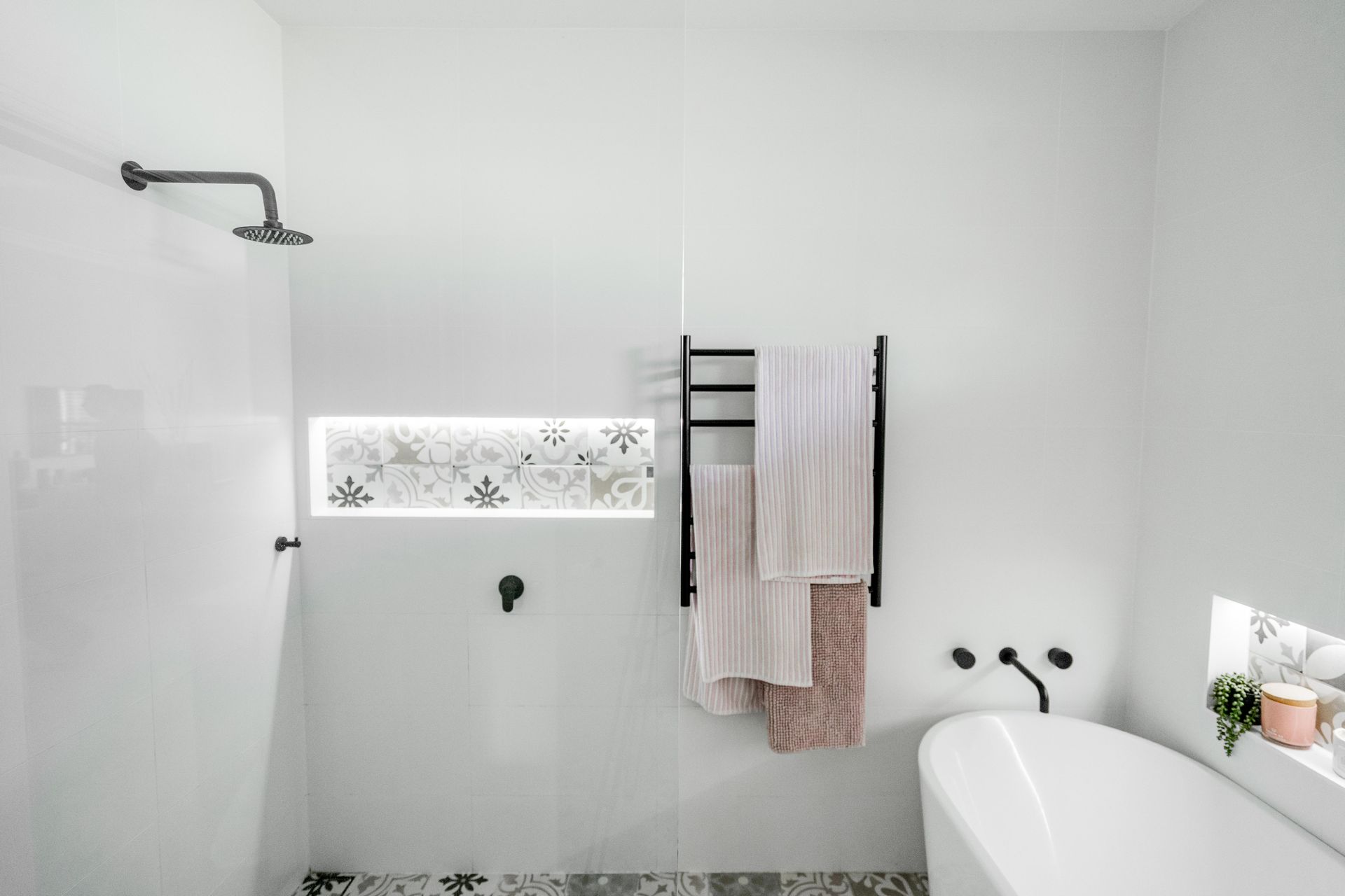 Minimal white bathroom with shower, decorative tile strip, towel rack, and bathtub — Cobra Plumbing & Bathrooms in Heathcote, NSW