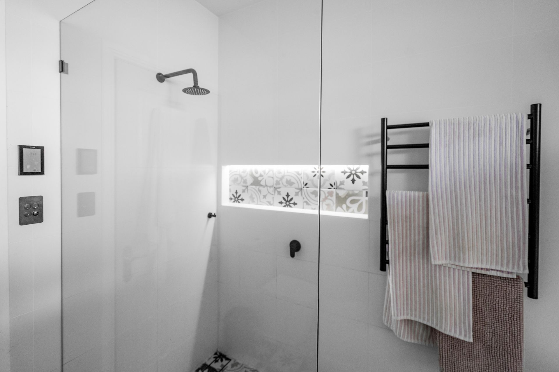 Modern white bathroom with shower, wall niche, and towels hanging on a rack — Cobra Plumbing & Bathrooms in Heathcote, NSW