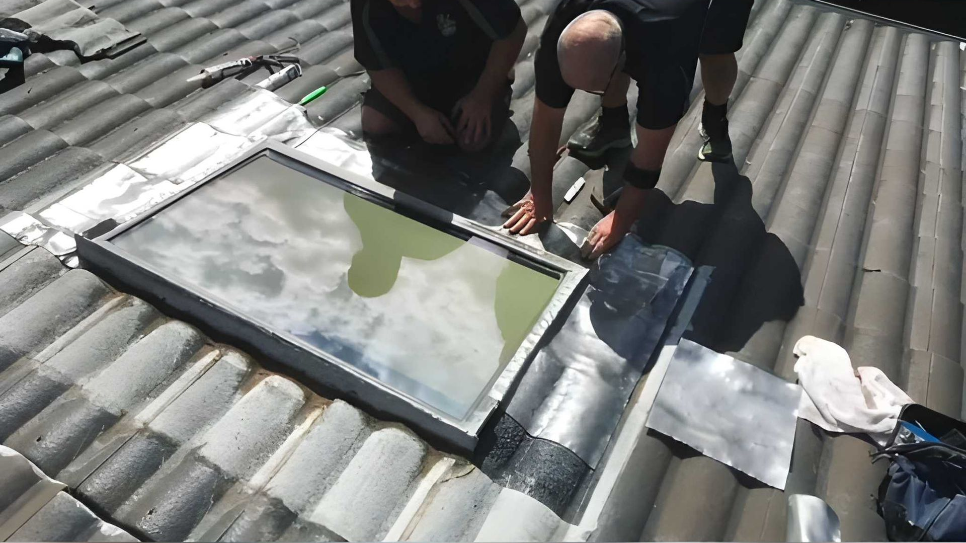 Two People Installing a Skylight on a Tiled Roof — Cobra Plumbing & Bathrooms in Heathcote, NSW