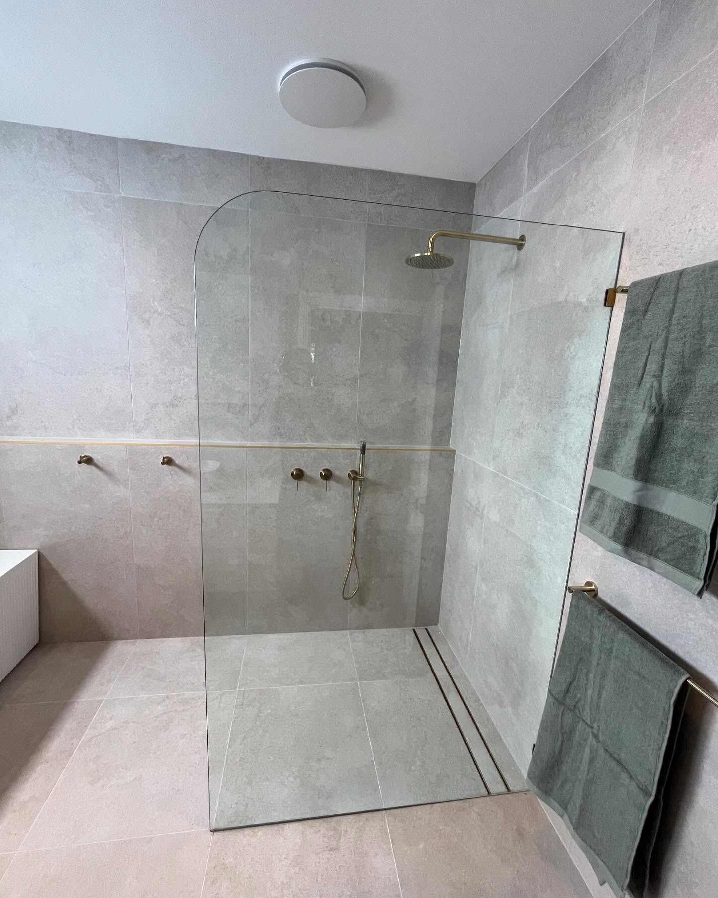 Modern Bathroom With Glass Shower Enclosure, Gold Fixtures, and Gray Tiles — Cobra Plumbing & Bathrooms in Kiama, NSW