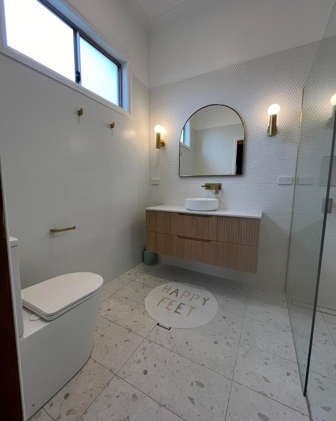 Modern Bathroom With White and Light Wood Elements, Arch Mirror, Decorative Tile, and Gold Fixtures — Cobra Plumbing & Bathrooms in Kiama, NSW