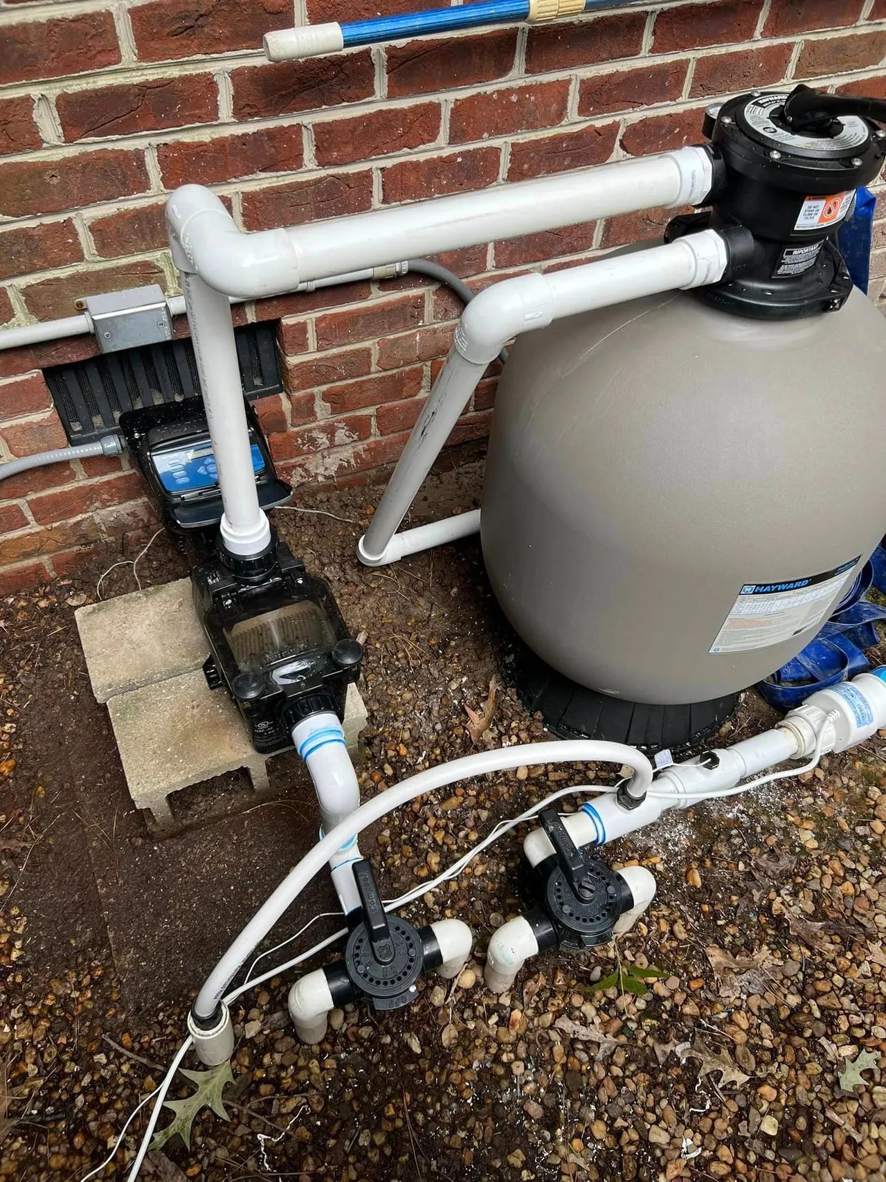 A swimming pool filter is sitting next to a brick wall.