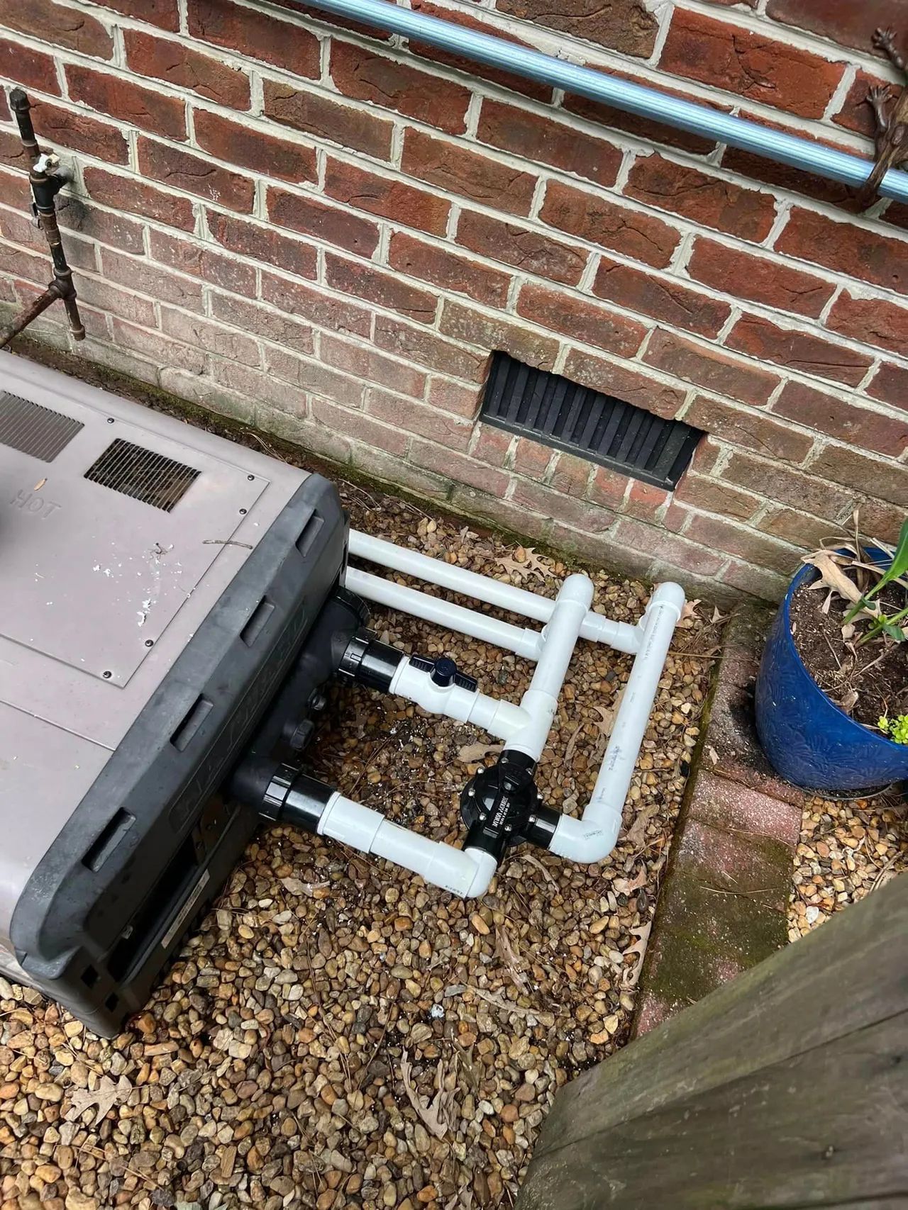 A computer is sitting on the ground next to a brick wall.