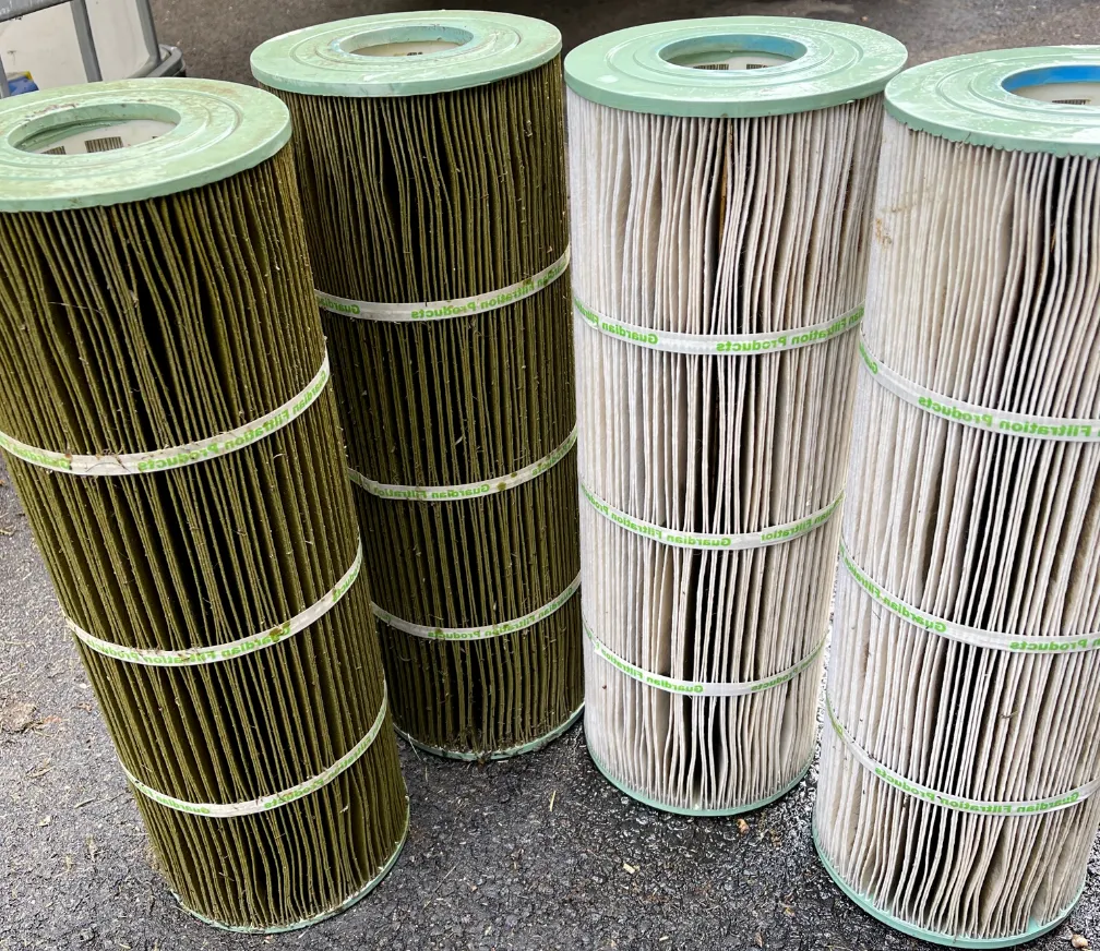 Four rolls of filter cartridges are stacked on top of each other on the ground.