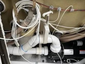 A close up of a bathtub with a lot of pipes and wires.