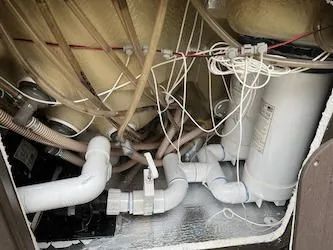 The inside of a bathtub with a lot of pipes and wires.