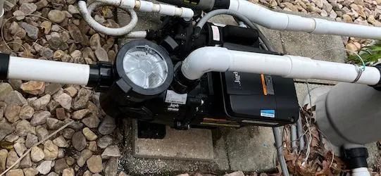 A swimming pool pump is sitting on top of a concrete block.