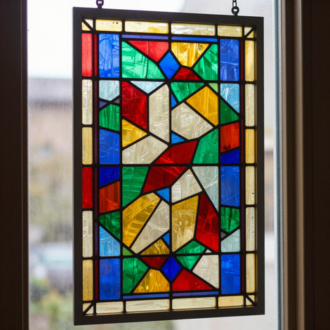 Colorful geometric stained-glass panel hanging in a window