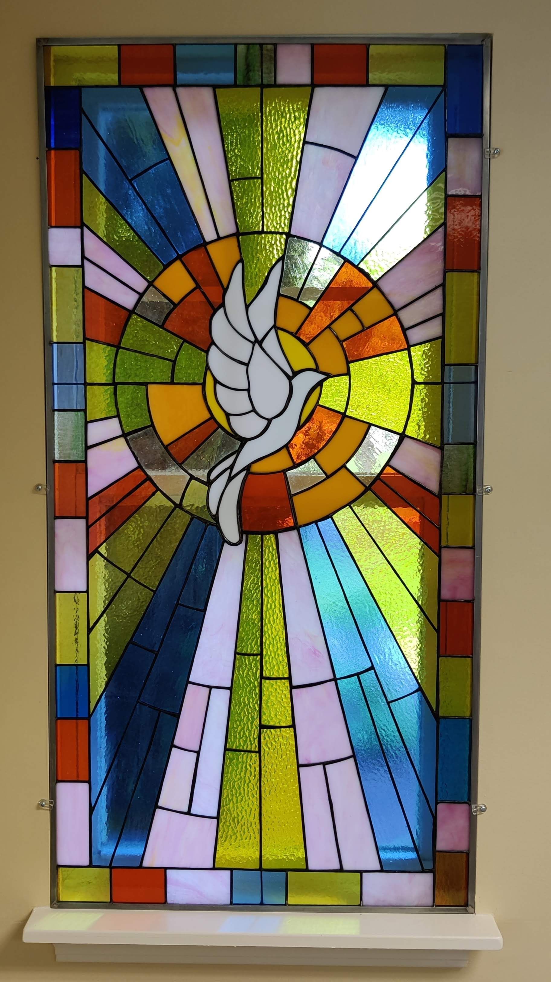 Colorful abstract stained-glass window with a white dove motif and radiating geometric panes
