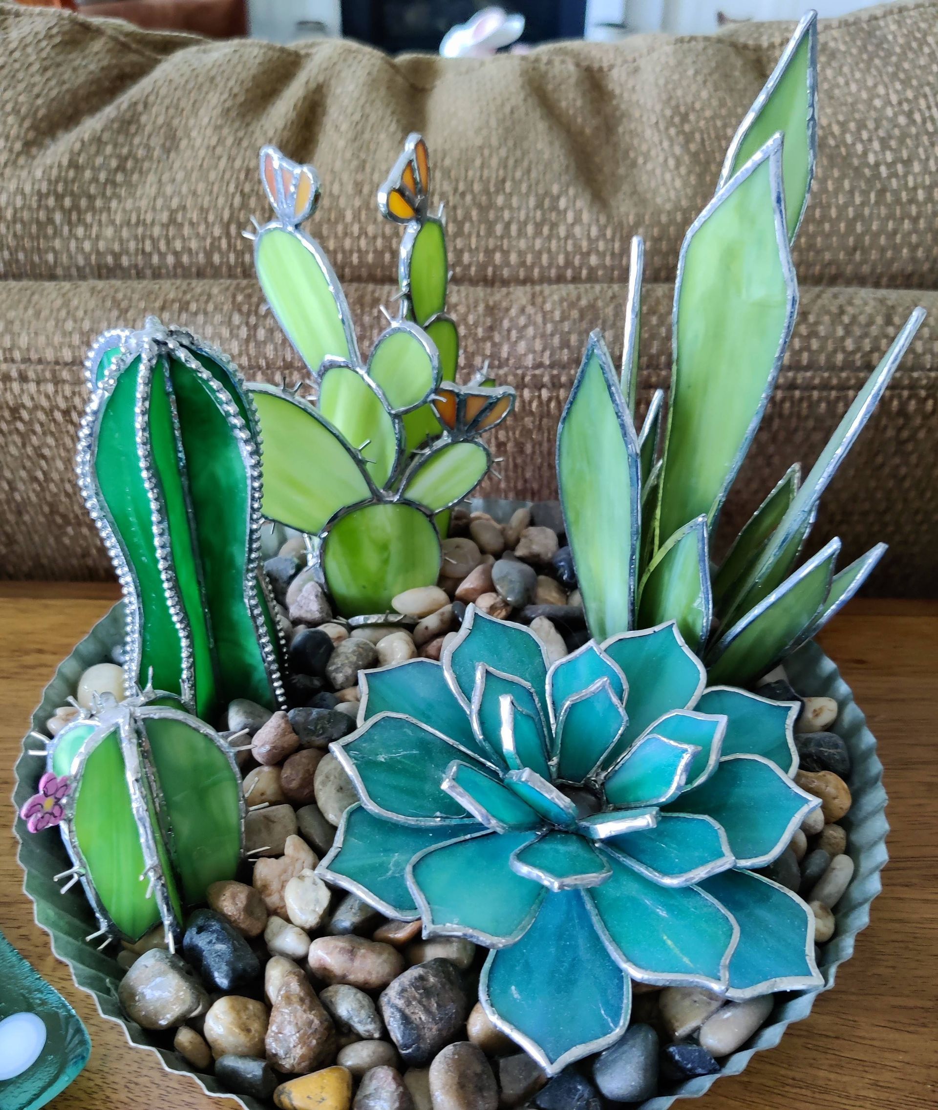 Pebble planter with handcrafted succulent decorations in green, teal, and silver on a table