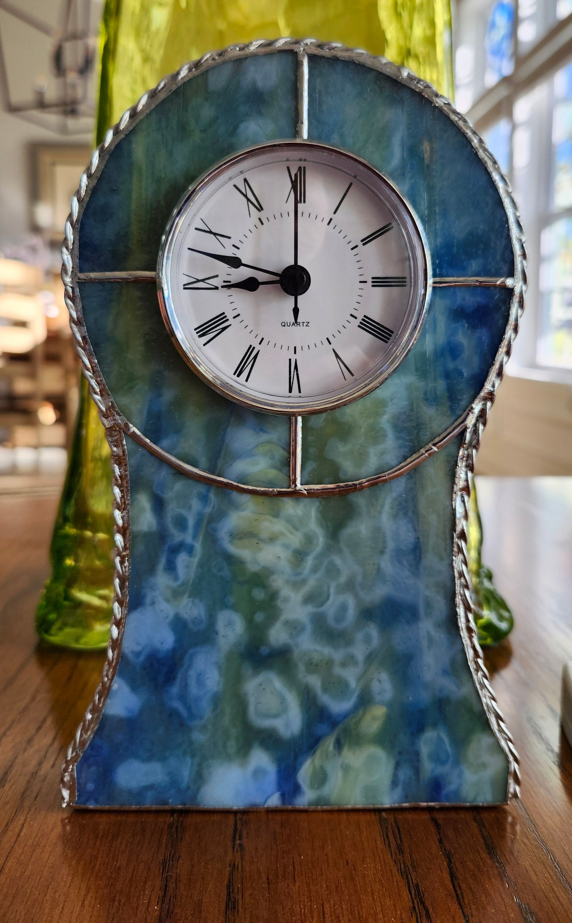 Blue stained-glass decorative clock with a round white face on a table