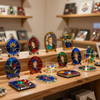 Colorful enamel pins and small ornaments displayed on a wooden shelf in a shop or studio.