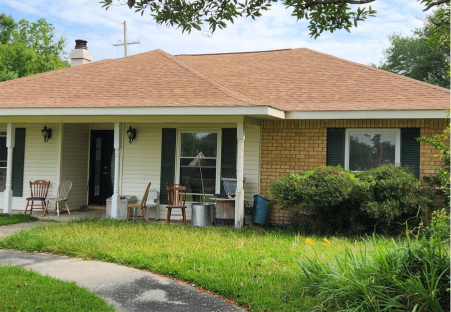 A brick house with a porch and chairs in front of it