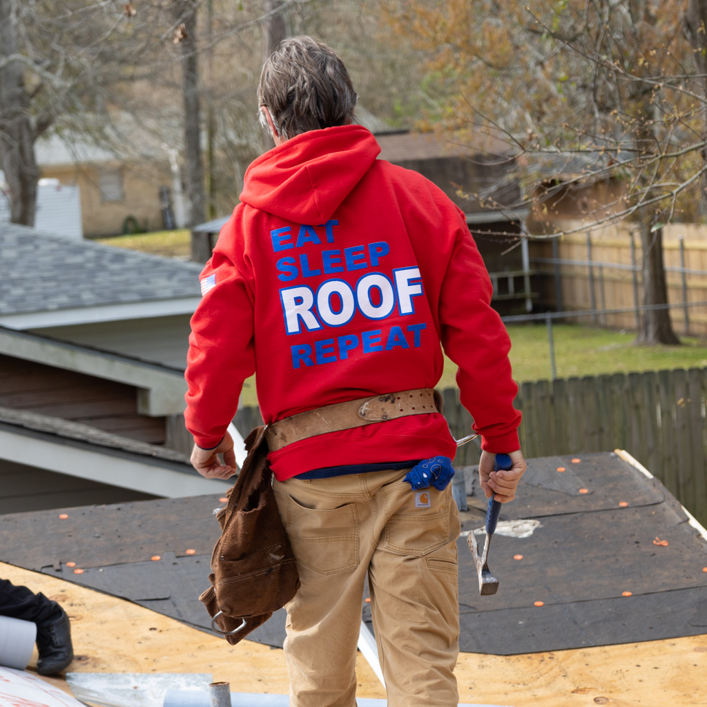 A man wearing a red hoodie that says eat sleep roof repeat