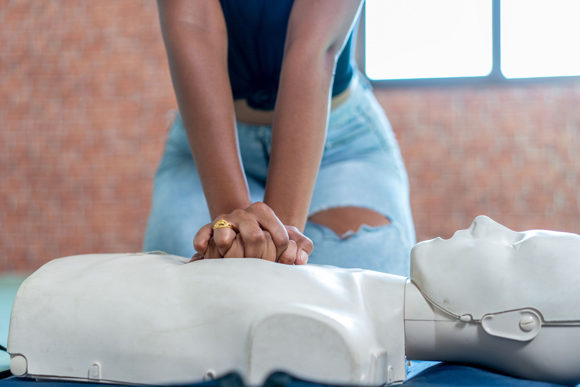 A woman is practicing first aid on a mannequin