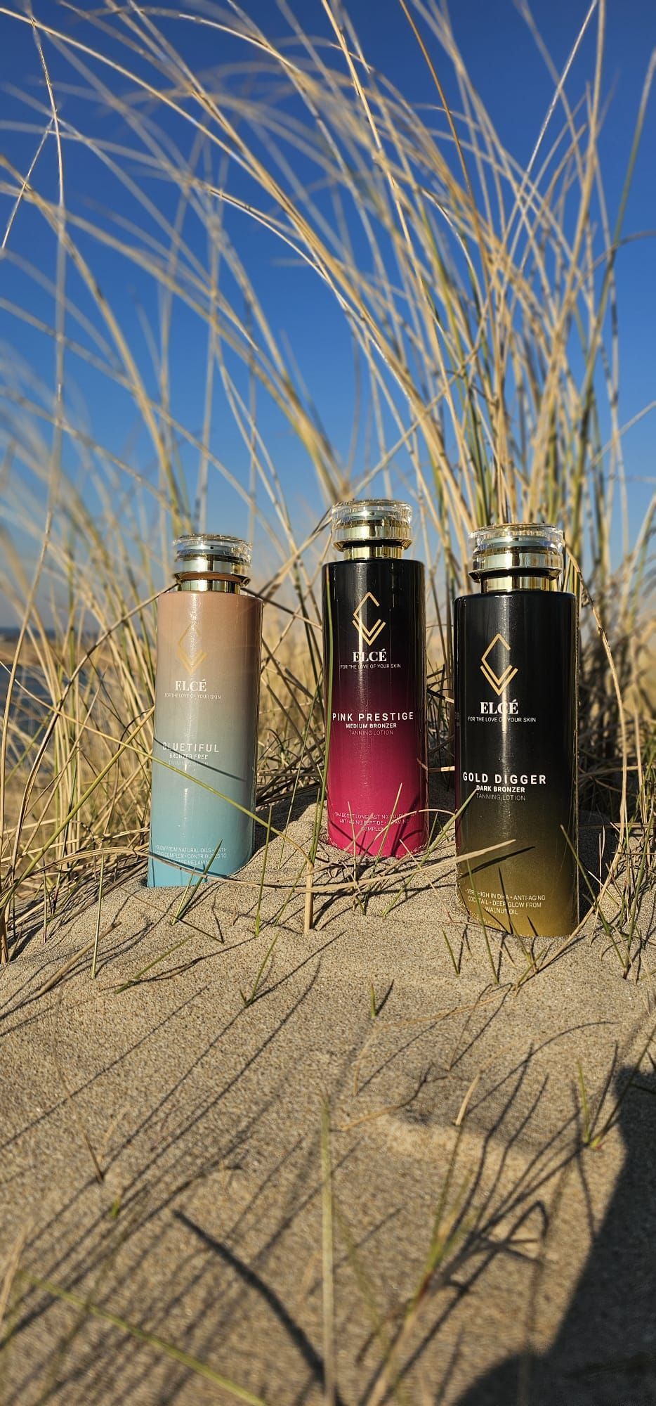 Drie flesjes parfum staan ​​op een zandstrand.