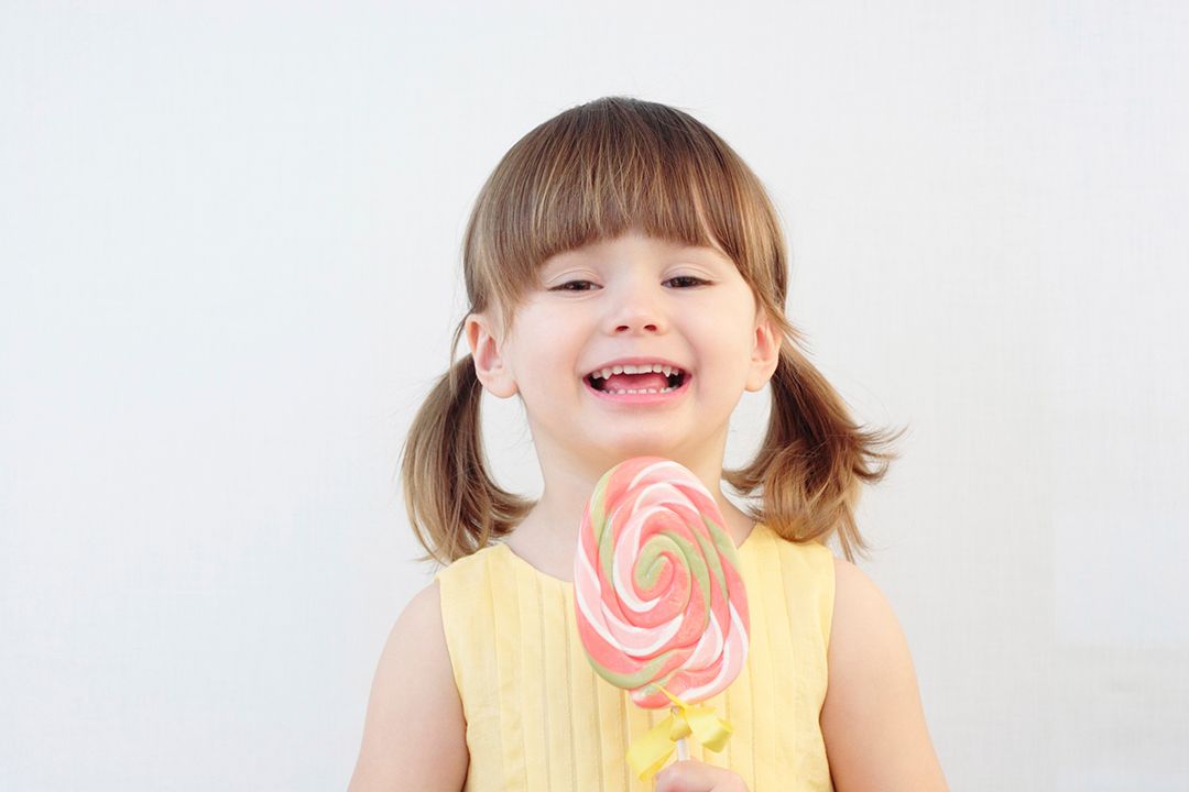 Una niña está comiendo una piruleta de colores.