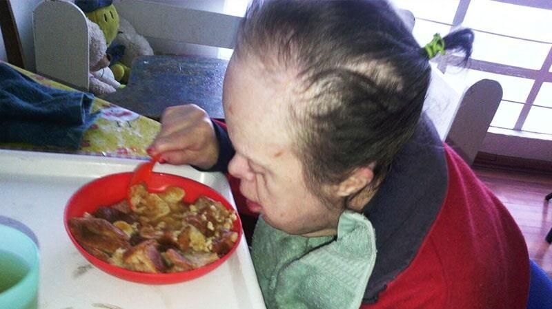 Una mujer está comiendo un plato de comida con una cuchara.