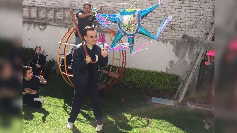 Un grupo de personas está jugando con una piñata en un patio trasero.