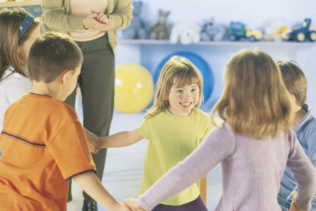 Un grupo de niños se toman de la mano formando un círculo.