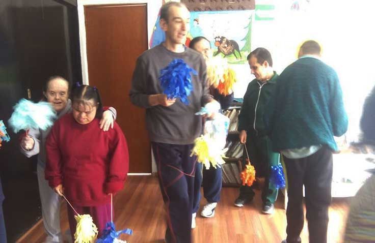 Un grupo de personas están de pie en una habitación sosteniendo pompones.