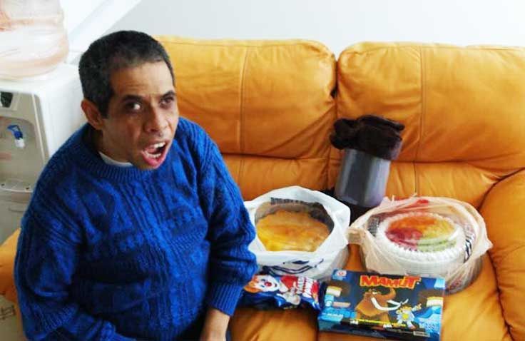Un hombre con un suéter azul está sentado en un sofá comiendo comida.