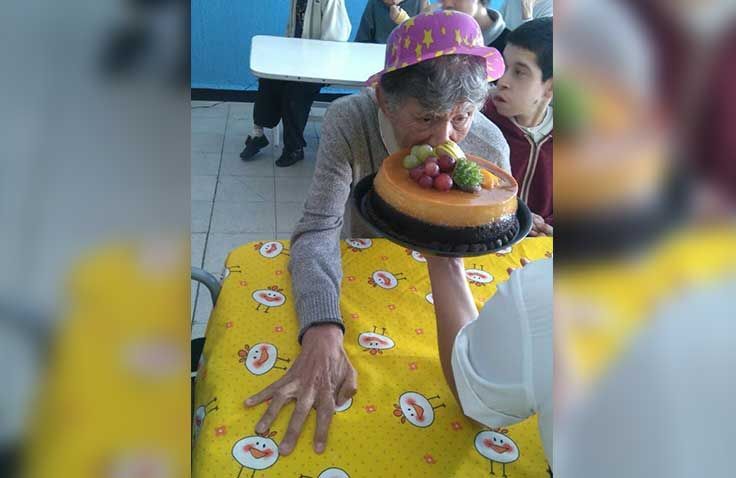 Una mujer que lleva un sombrero de cumpleaños está soplando una vela en un pastel.