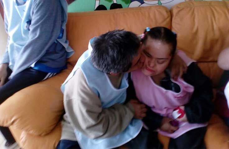 Un hombre besa a una chica en la mejilla mientras está sentado en un sofá.