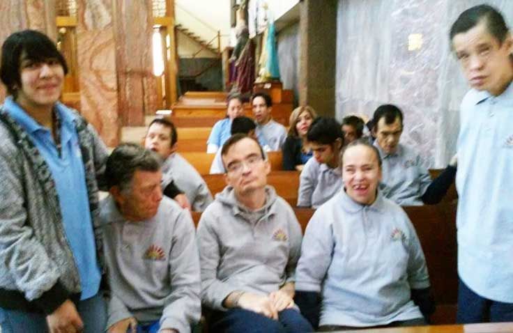 Un grupo de personas están de pie y sentadas en una iglesia.