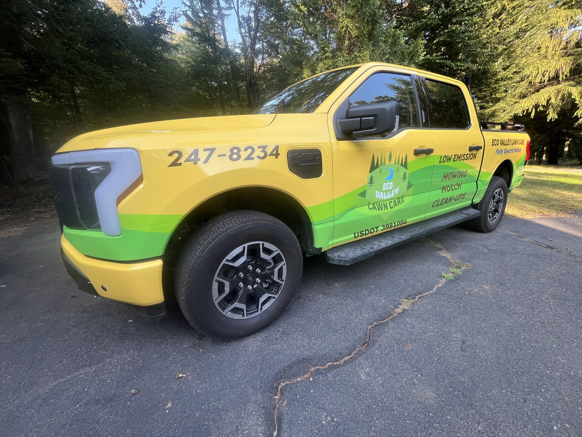 Yellow and green Ford F-150 Lightning work truck with company logo parked on asphalt.
