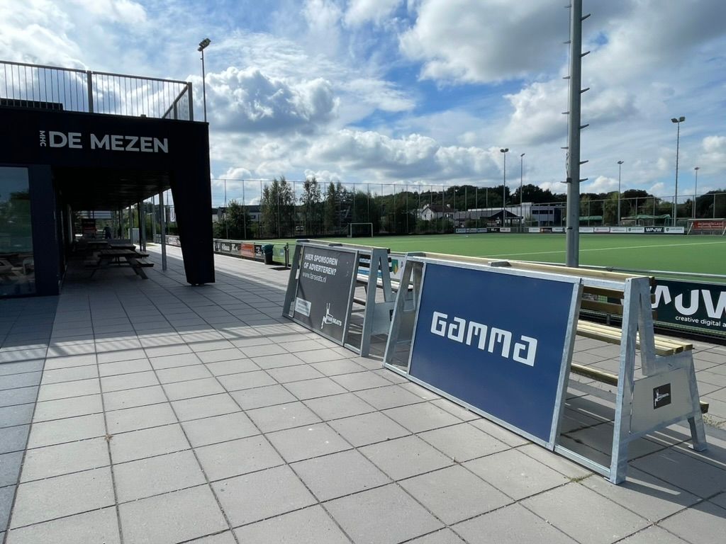 Een openlucht sportterrein in Harderwijk bij Hockeyclub de Mezen onder een bewolkte hemel.