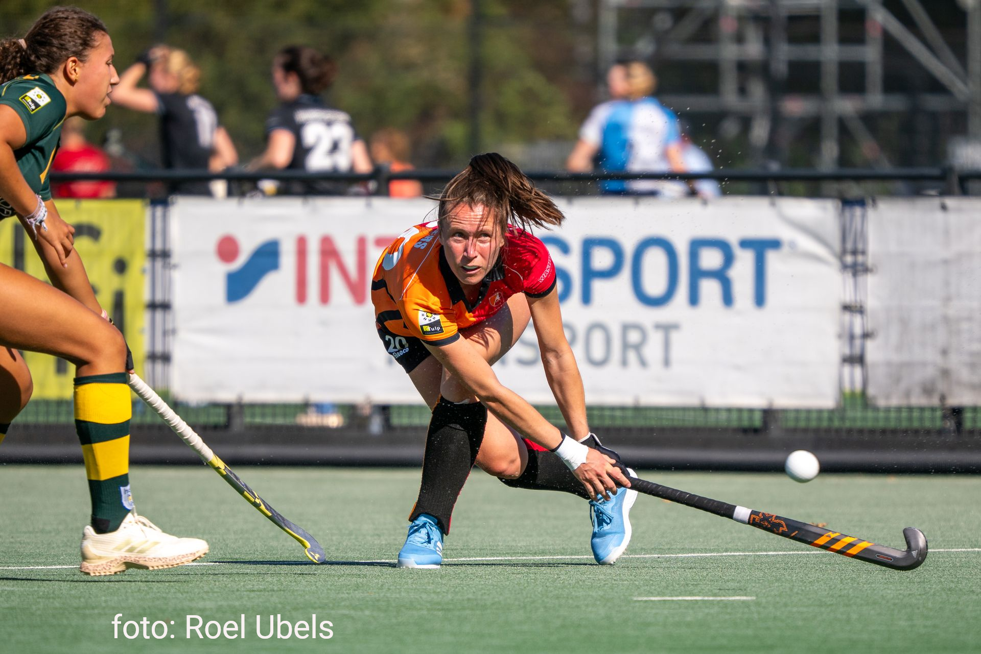 Hockeyspeler in oranje, met de ogen op de bal gericht, stick in de hand, klaar om te slaan.