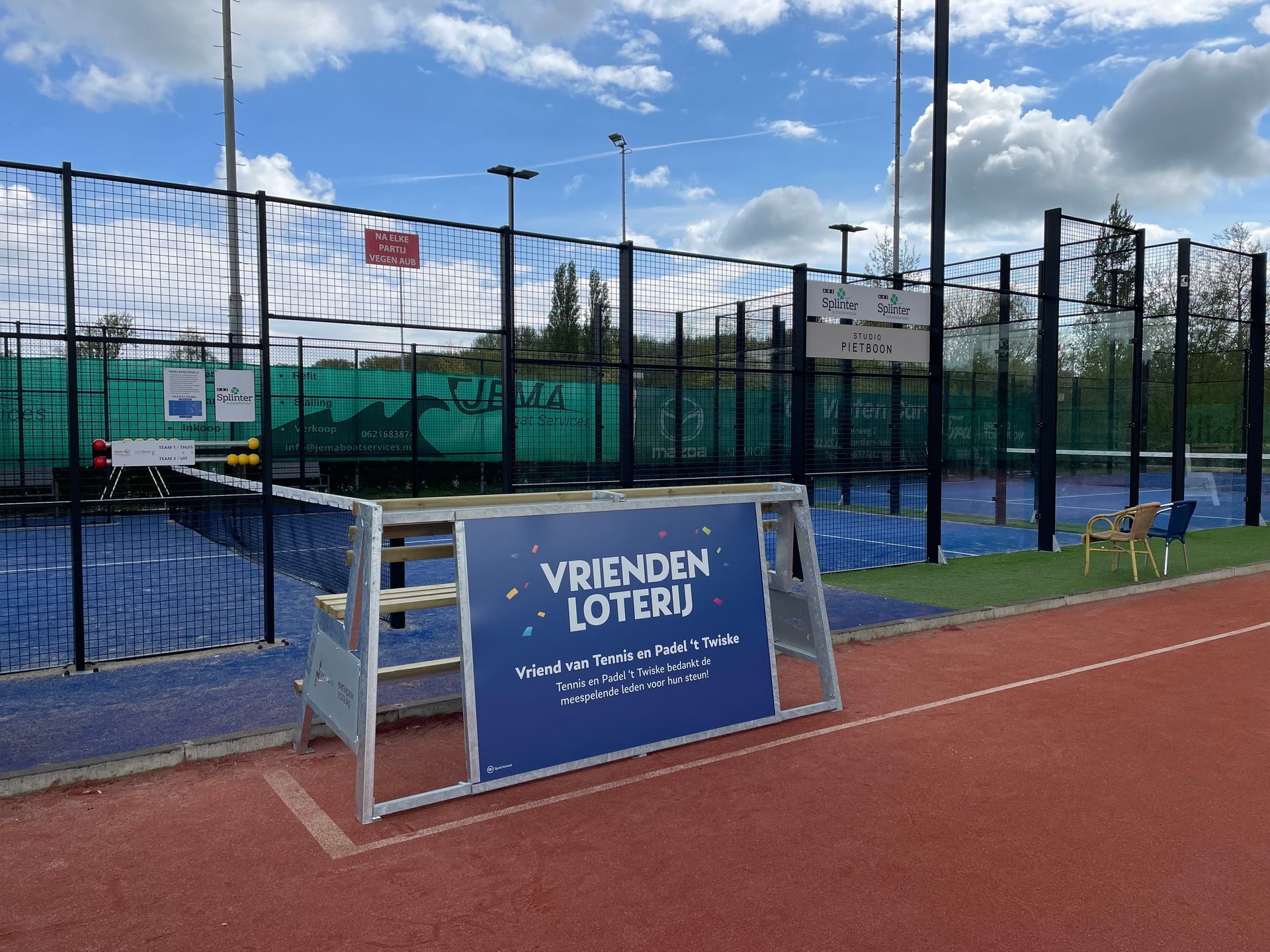 Padelbaan met een reclame bank van Fanseats, vlakbij een tennisbaan 
