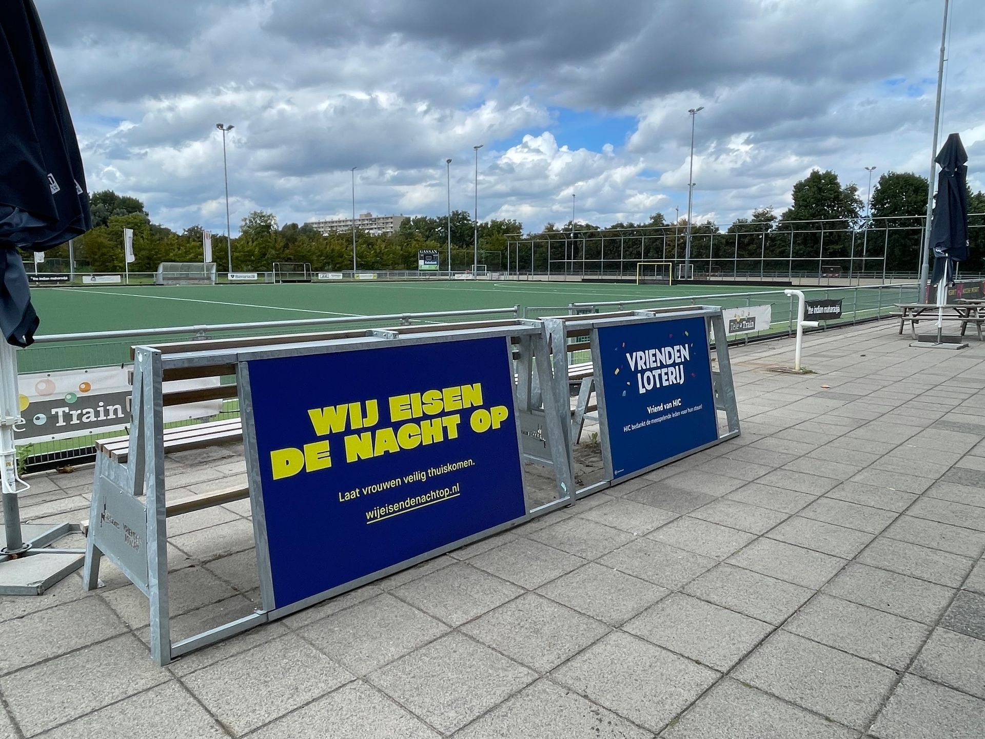 Tribune banken met reclame bij een hockey veld Op de borden is Nederlandse tekst zichtbaar 