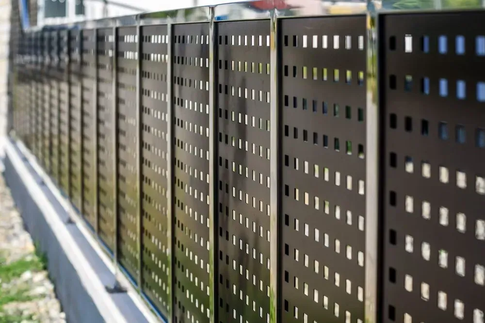 A Close Up Of A Metal Fence With Holes In It — Coastal Blind Installations In Agnes Waters, QLD