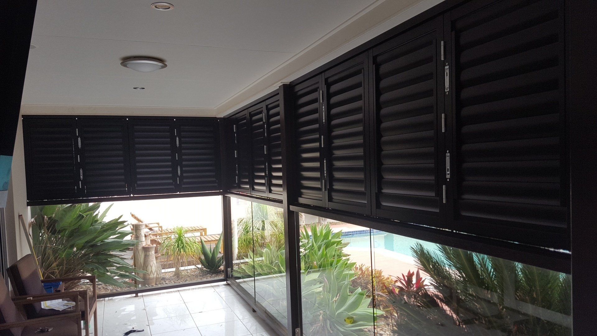 Black Shutters Over Glass Railing — Shutters in Bundaberg, QLD
