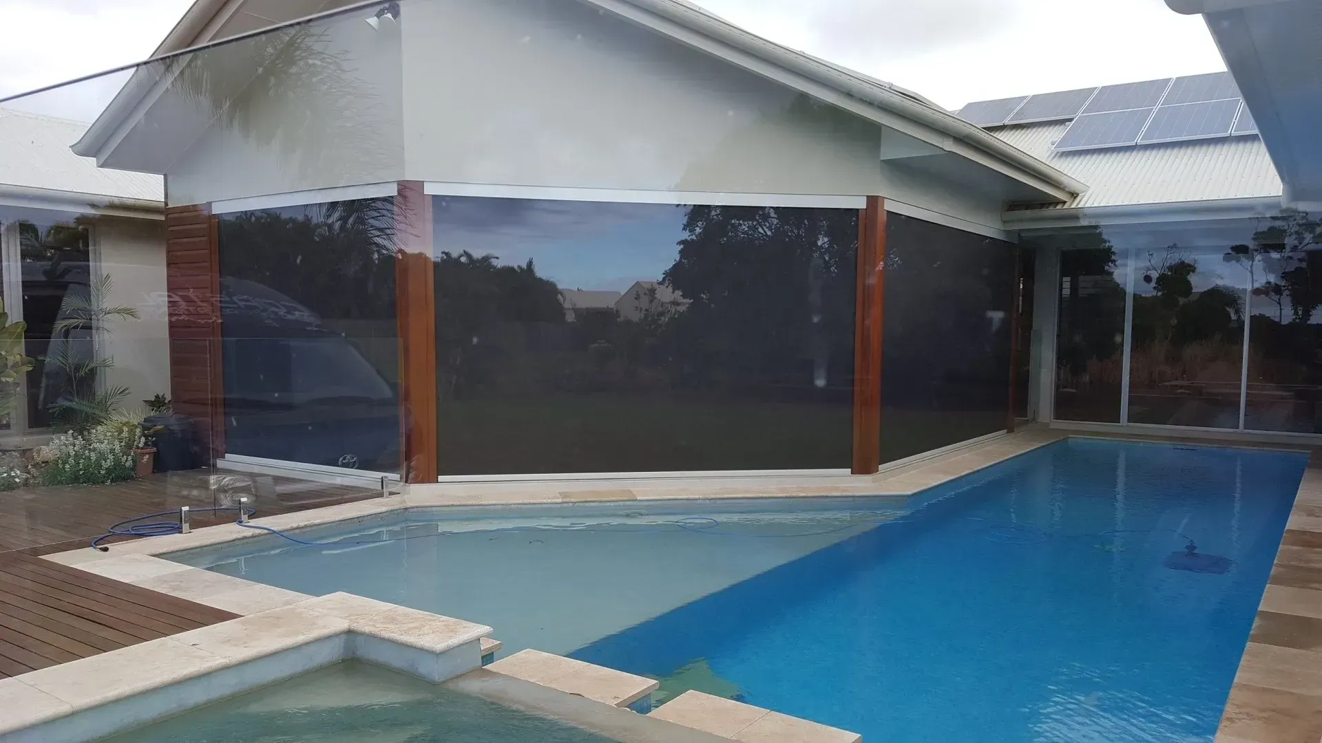 There is a large swimming pool in the backyard of a house.