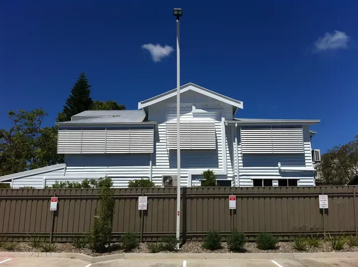 A Large White House With A Fence Around It — Coastal Blind Installations In Kensington, QLD