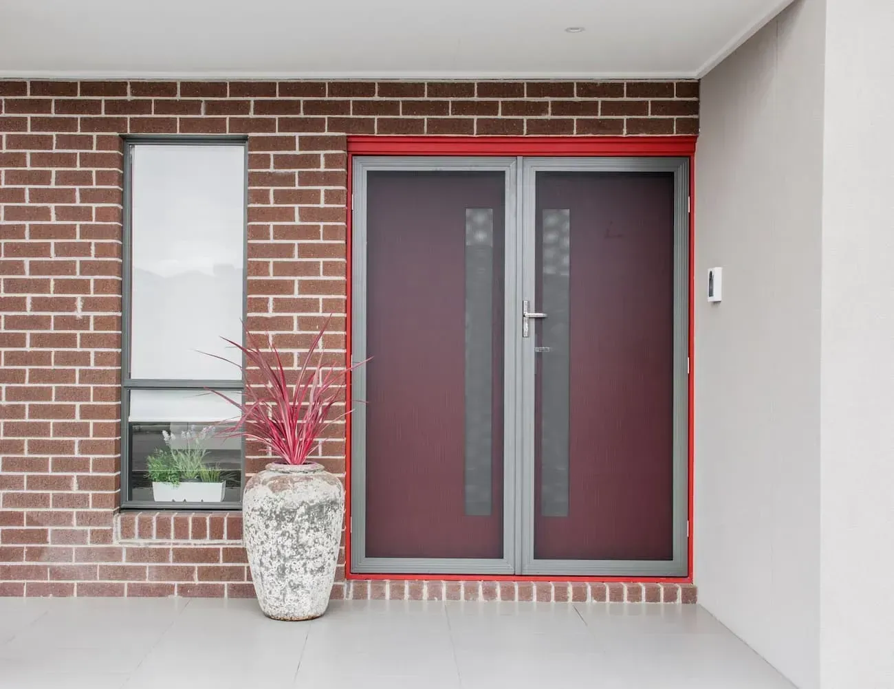A Brick Building With A Red Door And A Potted Plant In Front Of It — Coastal Blind Installations In Agnes Waters, QLD