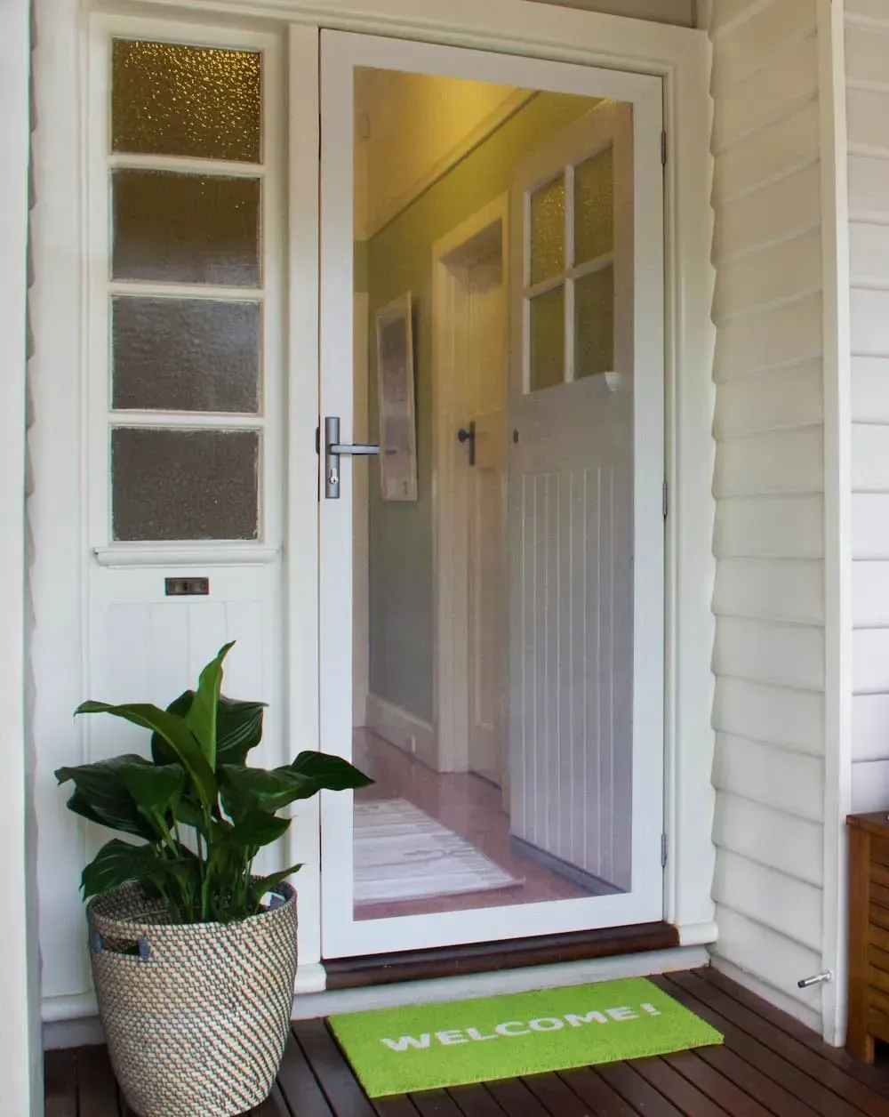 A Green Welcome Mat Sits In Front Of A Glass Door — Coastal Blind Installations In Agnes Waters, QLD