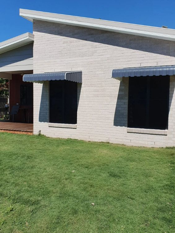 A White Brick House With Two Windows And A Lawn In Front Of It — Coastal Blind Installations In Kensington, QLD